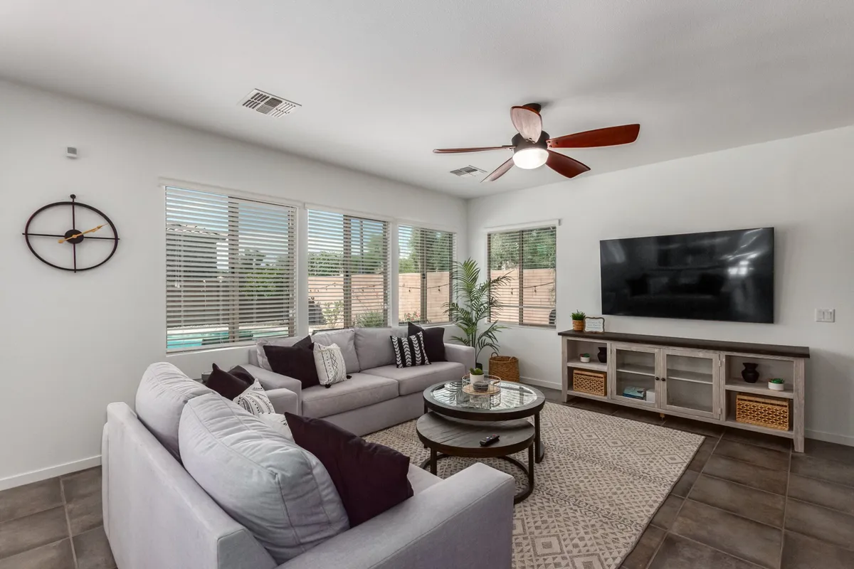 A comfortable lounge area with a plush sofa, coffee table, television, and expansive windows letting in natural light. The setting is perfect for relaxing, watching movies, playing games, or unwinding after a day of adventure.