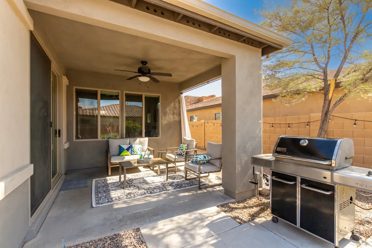 This exterior image features an inviting outdoor seating area with stylish cushions and a grill, all set on a patio space perfect for both relaxation and entertaining. The setup is open to the yard, suggesting ample room for pets to roam and play. The environment is casual and welcoming, ideal for enjoying time outdoors with a dog.