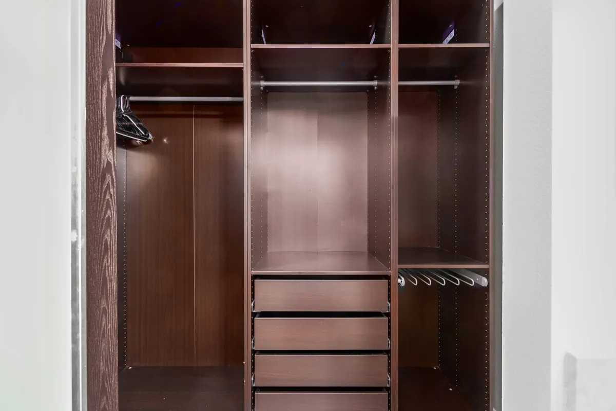 A spacious, well-organized walk-in closet with wooden shelves, hanging rods, and drawers, offering ample storage and a sense of order.