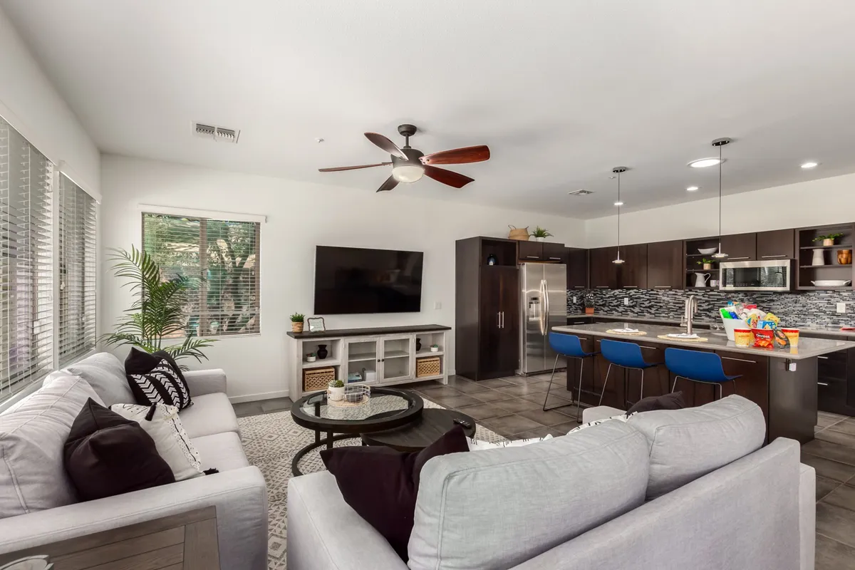 A cozy living area with comfortable sofas facing a large TV, adjacent to a modern kitchen. The casual, inviting atmosphere is perfect for relaxing, watching movies, or enjoying group activities.